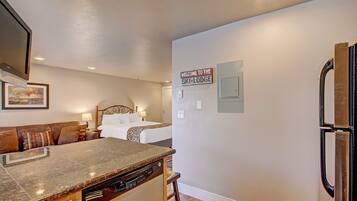 A kitchen with granite countertops, a dishwasher, and a refrigerator. There is a sign on the wall that reads "Welcome to the Ski Lodge."