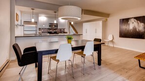A modern kitchen with stainless steel appliances, a dining area with a large table and chairs, and a staircase leading to another level. - Sts. Johns 2507 (Keystone)