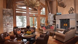 A log cabin interior with leather furniture, a stone fireplace, and a deer head mounted on the wall. - Ski In/out Lodge With Private Lifts, 2br 2ba Next To Golf 2 Bedroom Condo by RedAwning (Avon)