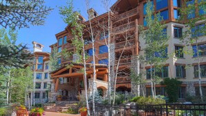 A multi-story hotel with stone and wood exterior, balconies, and a landscaped courtyard. - Ski-in/ Ski-out 3br 3.5ba Forest + Mountain Views Sleeps 8 3 Bedroom Condo by RedAwning (Avon)