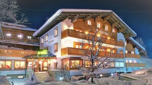 Un hotel de varios pisos con un estilo arquitectónico alpino tradicional, con balcones y un paisaje cubierto de nieve.