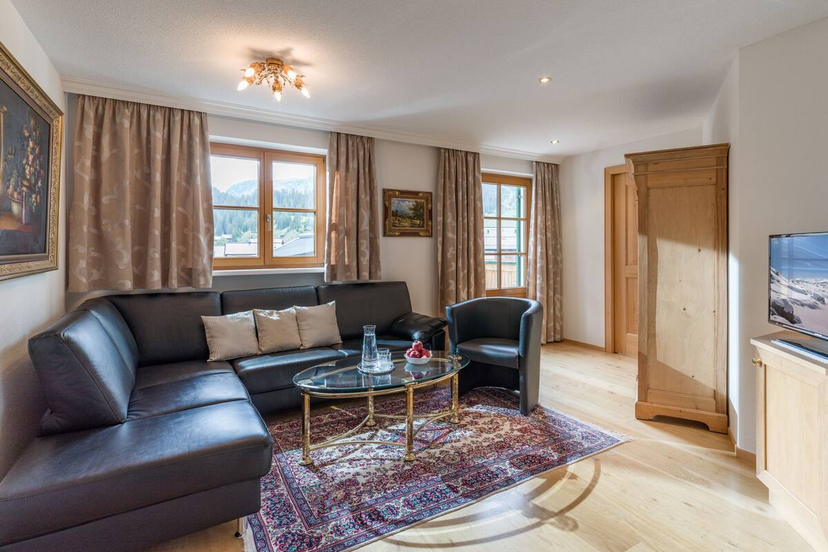 A modern living room with a leather sofa, a glass coffee table, and a patterned rug.