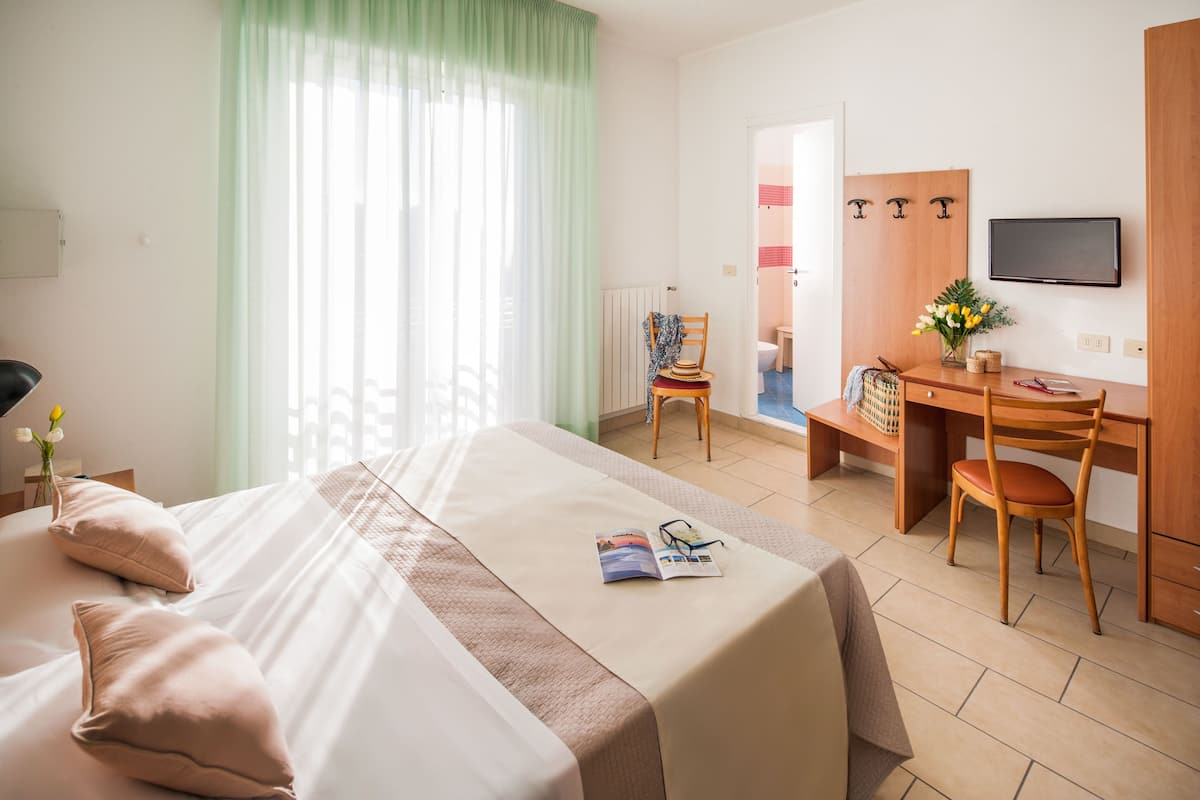 Une chambre d’hôtel équipée d’un lit, d’un bureau, d’une chaise, d’une télévision et offrant une vue sur la salle de bain.