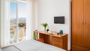 A bedroom with a bed, a desk, a chair, a TV, and a wardrobe. - Hotel Europa (Finale Ligure)
