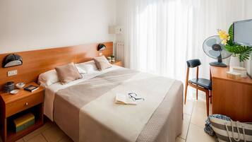 Habitación de hotel ordenada con cama, mesitas de noche, escritorio y una silla.