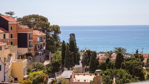 A coastal residential area with multi-story buildings, a clear view of the sea, and a mix of trees and vegetation. - Hotel Europa (Finale Ligure)