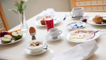 Una mesa de desayuno con diferentes alimentos y un jarrón de flores.
