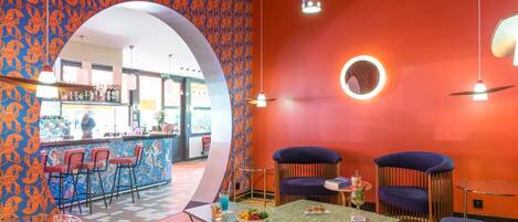 Een levendige inrichting met een bar, zitplaatsen en een ronde lamp aan de muur.