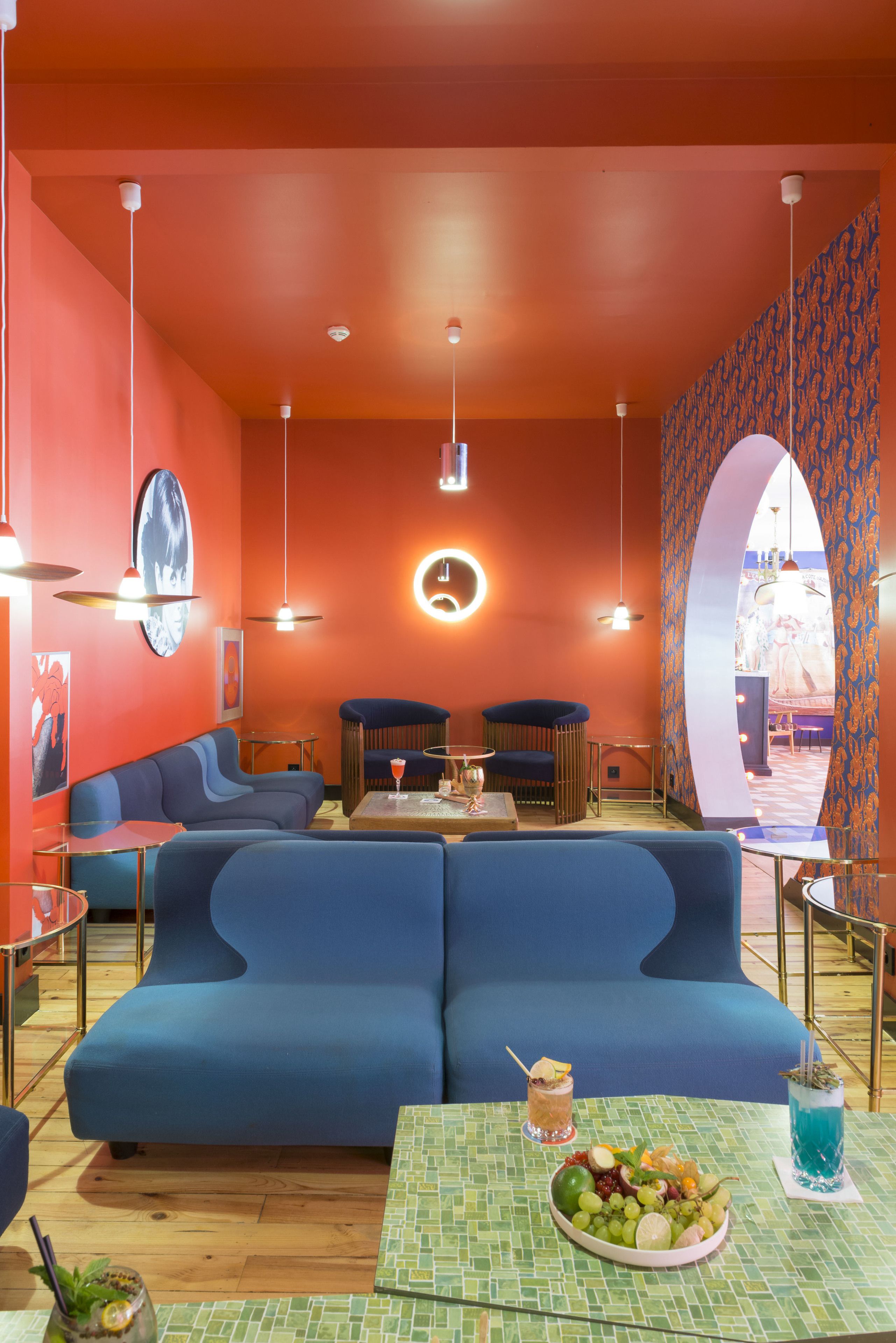 Ein lebendiger Innenraum mit einem blauen Sofa, einem runden Tisch mit einer Obstplatte und Blick durch einen Bogen.