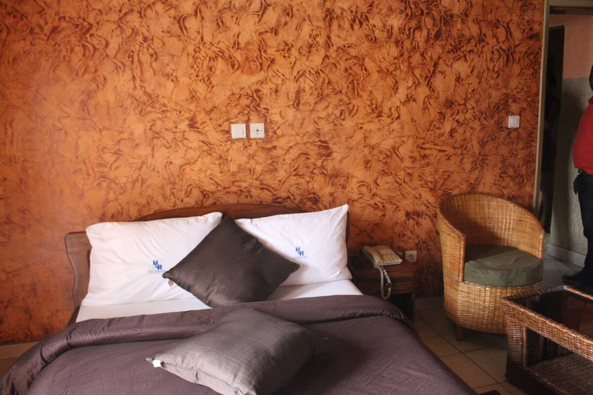 Habitación de hotel con cama, una silla y teléfono.