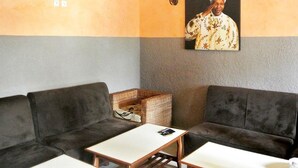 A room with two dark sofas, a small table, and a wicker basket. - Hôtel La Renardière (Douala)