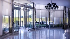 Un hall d’entrée spacieux et moderne, doté de grandes portes vitrées, d’un sol réfléchissant et d’un lustre.