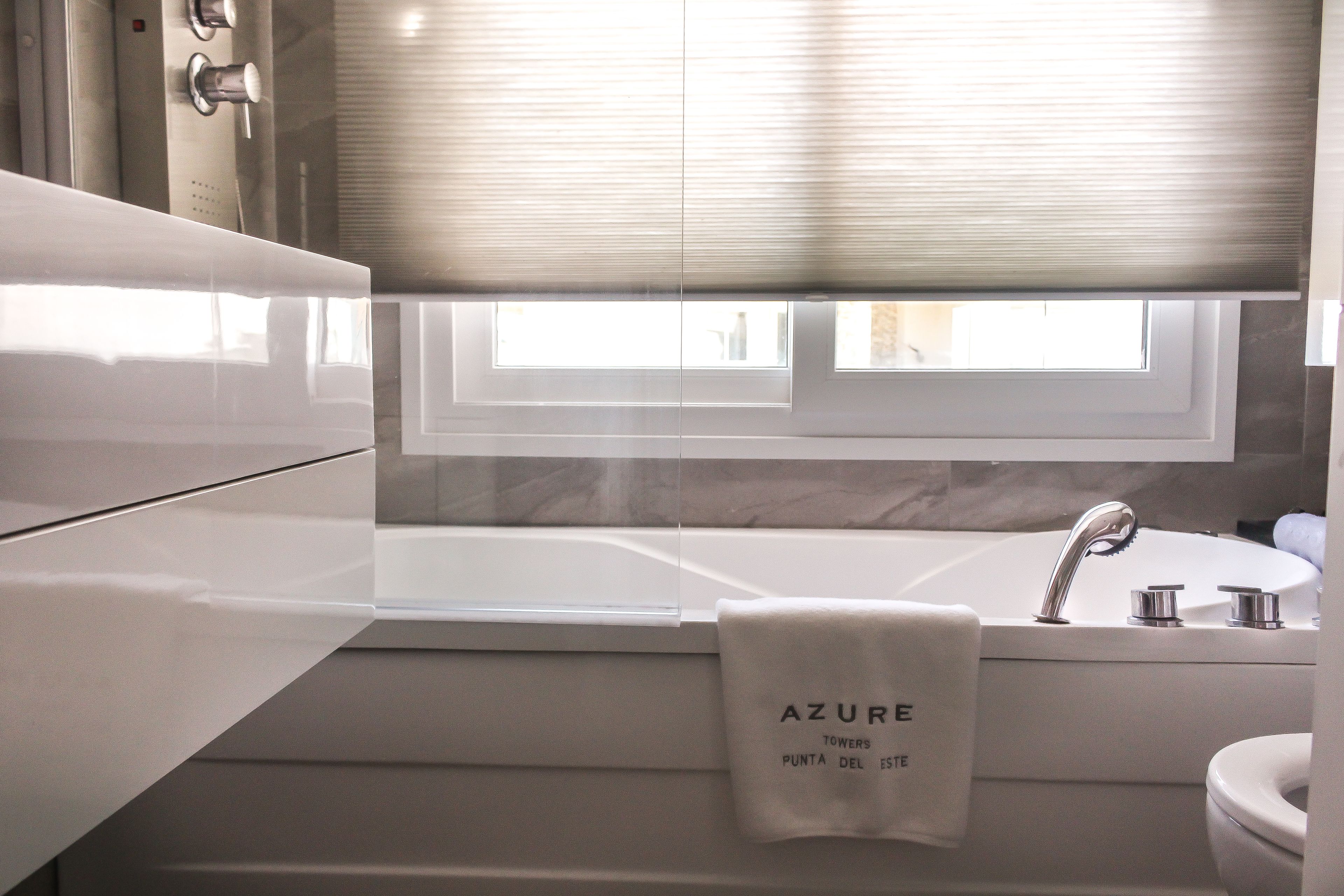 Un baño moderno con bañera, lavamanos y ventana con persianas.