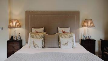 Una cama bien hecha con un cabecero capitonado, dos mesitas de noche con lámparas y almohadones decorativos.