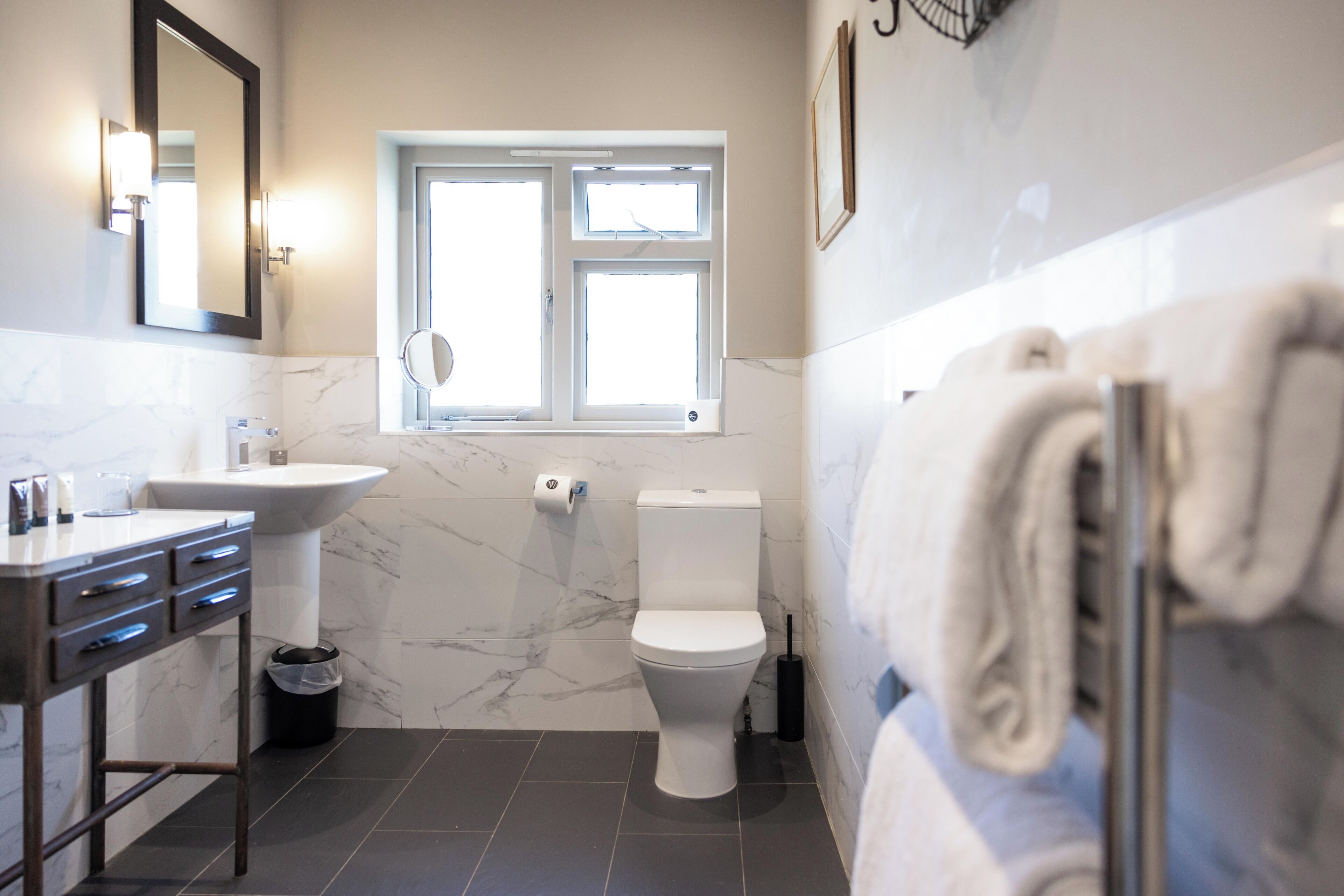 Une salle de bain avec un lavabo, des toilettes et une fenêtre.