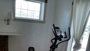 A room with a bench, an exercise bike, and an elliptical trainer. - Just You in Neepawa Vacation Home (Neepawa)