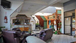 Un vestíbulo con sofás de cuero, un mostrador de recepción y una zona de bar.