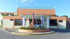 Un edificio con varias banderas, un estacionamiento y un cielo despejado.