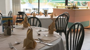 Una mesa de comedor dispuesta con servilletas dobladas, cubiertos y saleros y pimenteros.