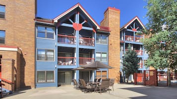 A multi-story building with balconies, a patio area with outdoor furniture, and a brick facade.