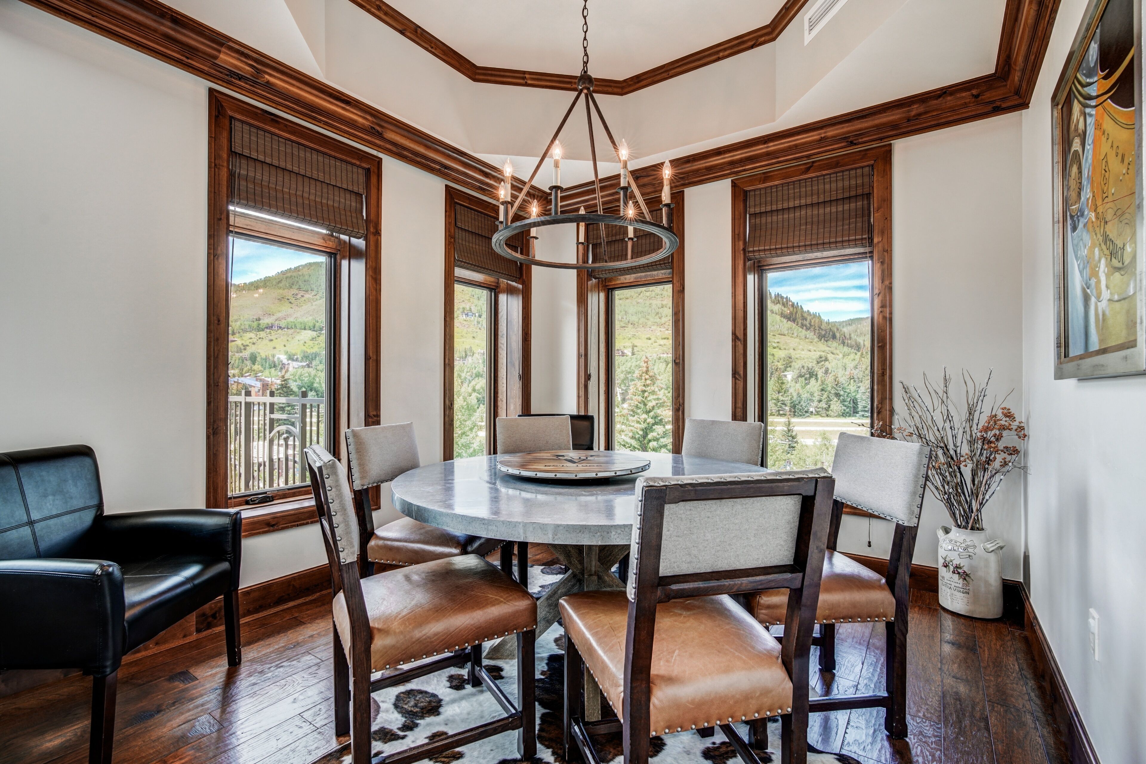 A dining area with a round table, six chairs, and a chandelier.