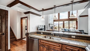 Una cocina con encimeras de granito, armarios de madera e iluminación colgante.