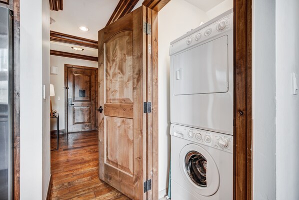A laundry room with a wooden door and a front-loading washing machine. - 3 BR Ritz-Carlton Residence with Valley Views by RedAwning - Save 20% on 7+ Nights! (Vail)