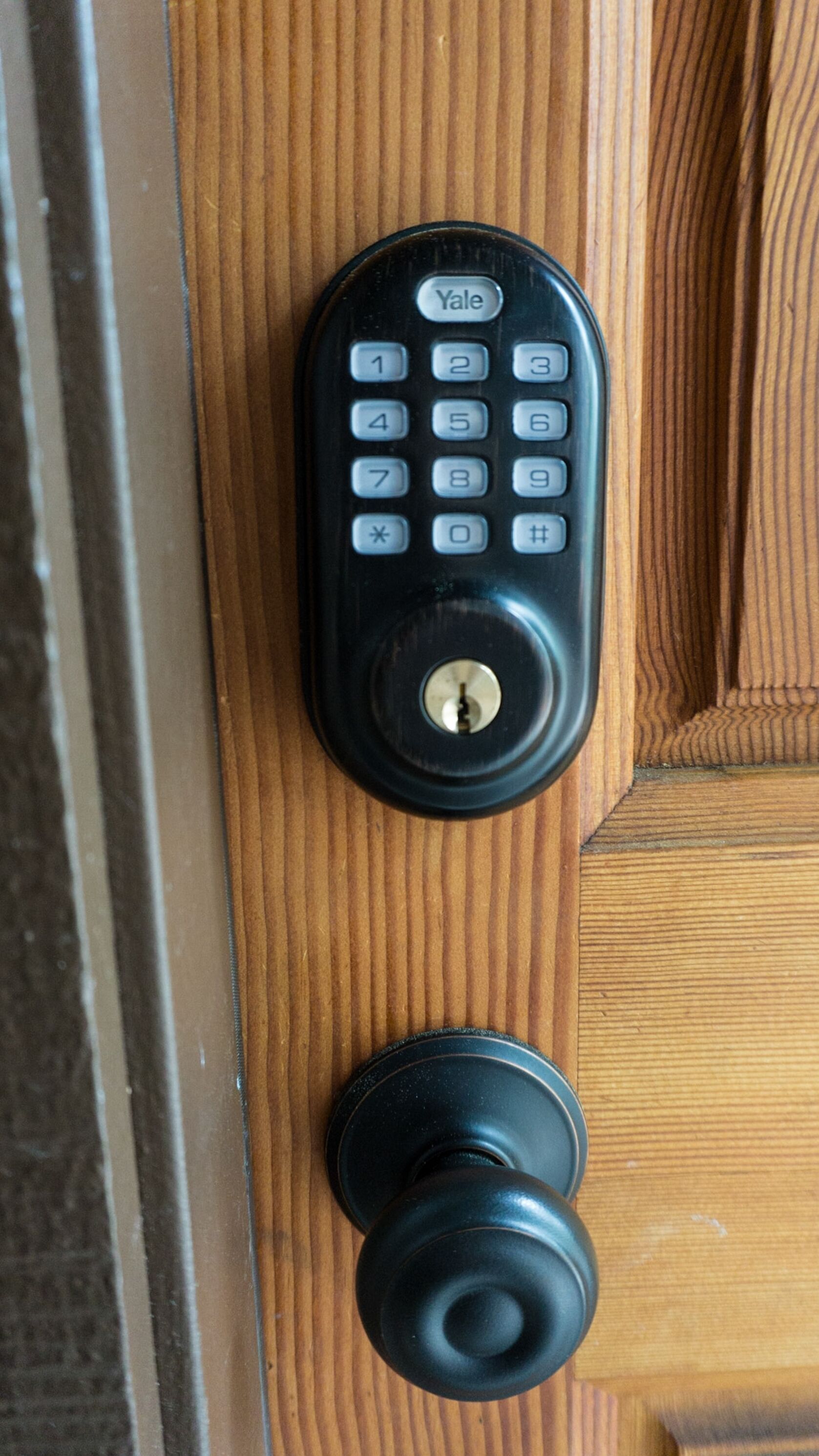 A Yale keypad lock on a wooden door.