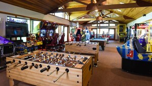An indoor recreational area with foosball tables, arcade games, and a pool table.