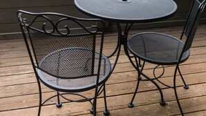 A wooden deck with two metal chairs and a table, overlooking a stone building with a Starbucks Coffee sign.