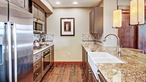 A modern kitchen with stainless steel appliances, a granite countertop, and wooden cabinets. - Luxury Studio  Steps From Winter Activities, Sleeps 4! Studio Bedroom Condo by RedAwning (Breckenridge)