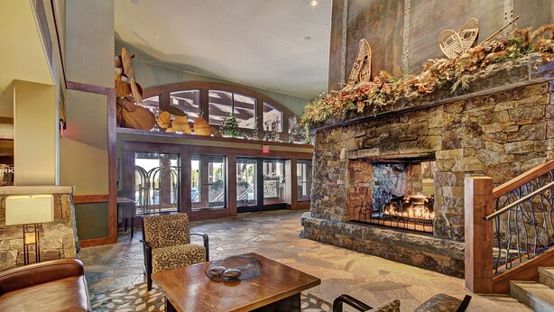 A spacious lobby with a stone fireplace, leather seating, and a high ceiling with large windows. - Luxury Studio  Steps From Winter Activities, Sleeps 4! Studio Bedroom Condo by RedAwning (Breckenridge)