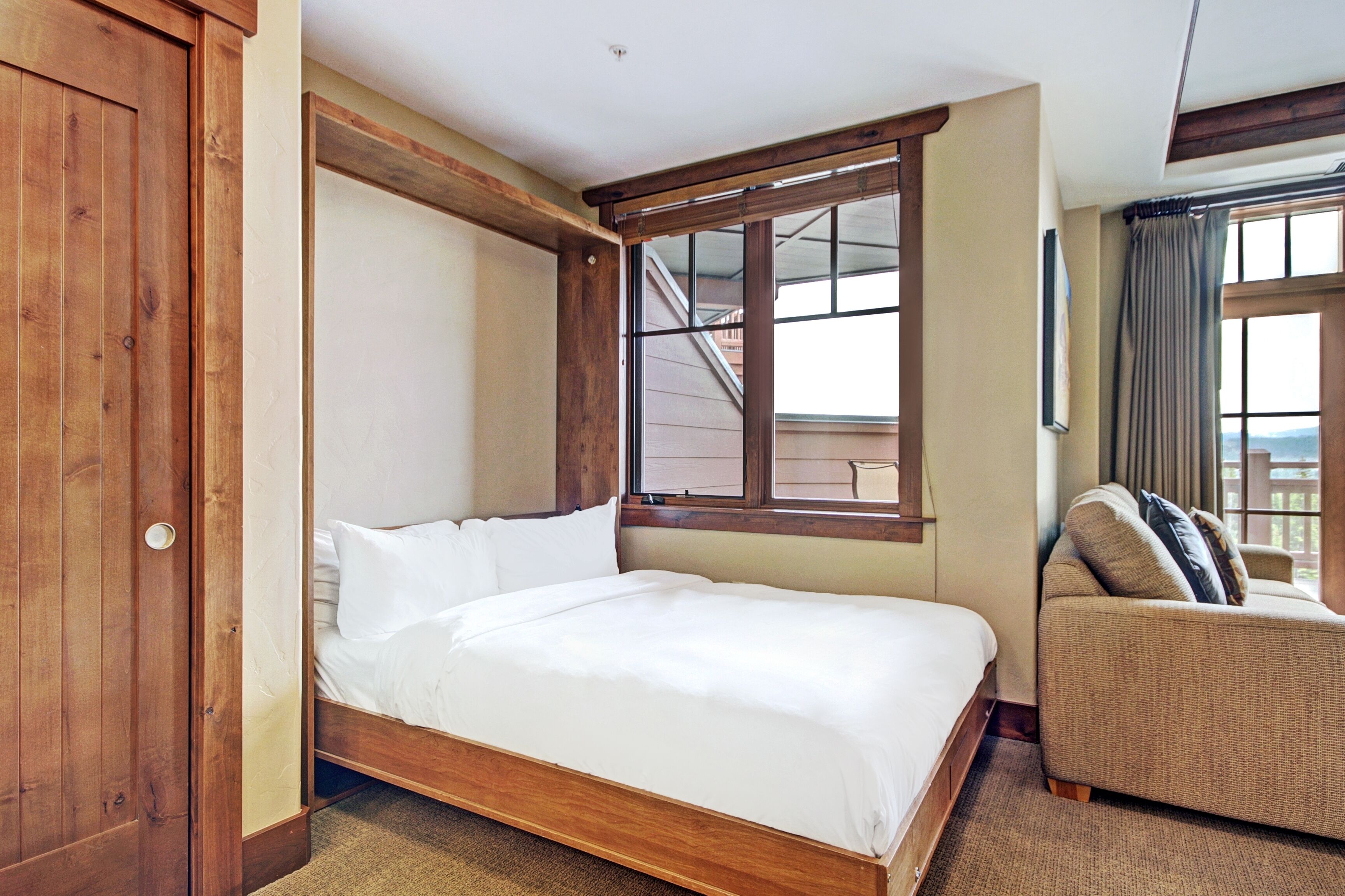 Een slaapkamer met een houten bed, een bank en een raam met uitzicht.