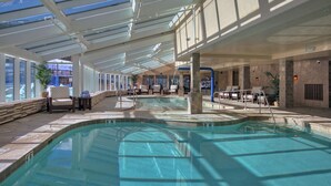 An indoor swimming pool with clear water, surrounded by lounge chairs and a sunlit ceiling with skylights. - Luxury Studio  Steps From Winter Activities, Sleeps 4! Studio Bedroom Condo by RedAwning (Breckenridge)