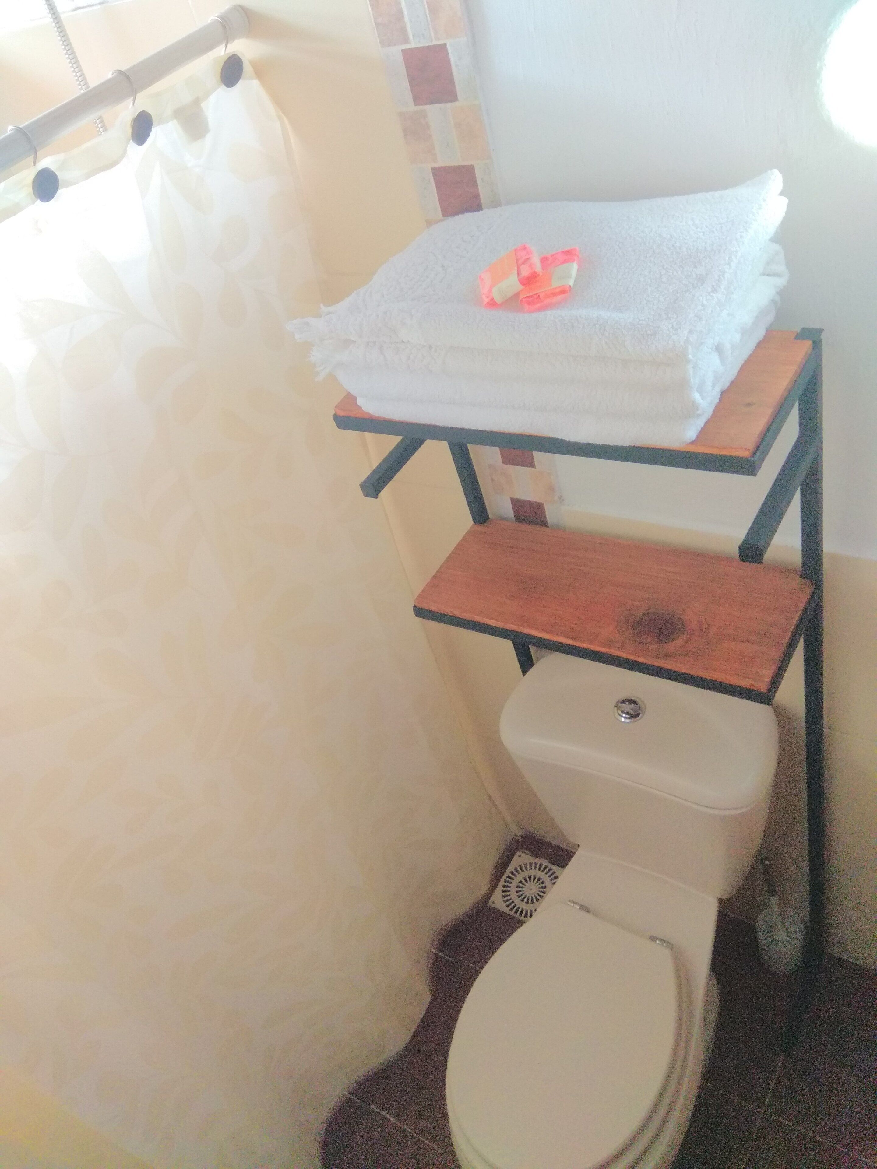 A bathroom with a toilet, a towel rack, and a shower curtain.