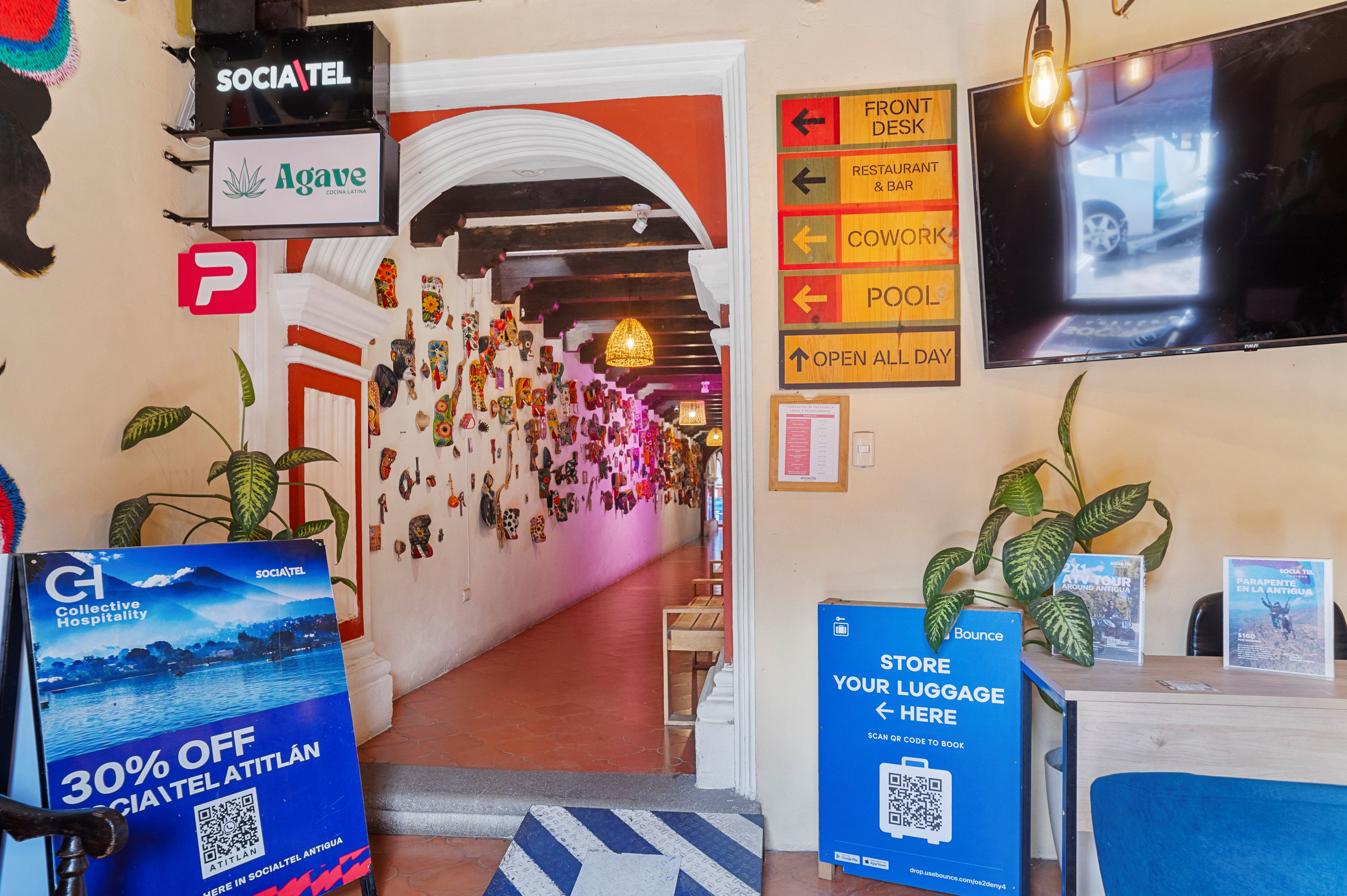 A hotel lobby with a reception desk, a wall with directional signs, and a QR code for luggage storage.