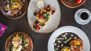 Une table à manger avec trois assiettes de nourriture, une tasse de café et un petit bol de yaourt.