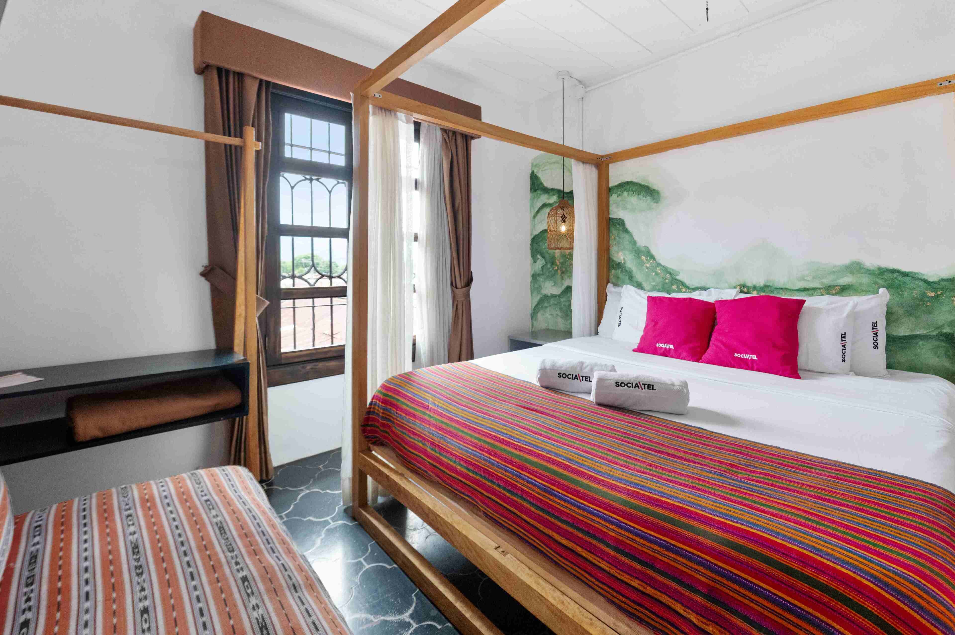 Une chambre d’hôtel avec un lit, un bureau et une fenêtre avec des rideaux.