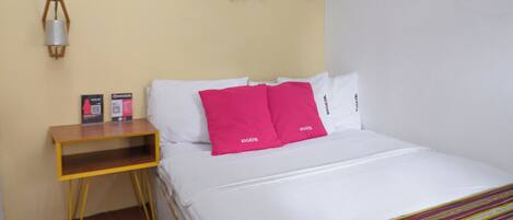 Ein Hotelzimmer mit Bett, Kissen, einem Nachttisch, einer Wandlampe und einer Holzdekoration an der Wand.