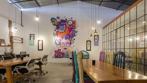 Une salle de réunion moderne, dotée d’une grande fresque murale, de tables en bois et de chaises colorées.