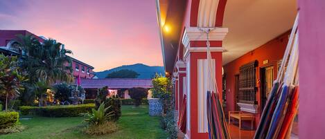 A hotel courtyard with a pool, palm trees, and a mountain in the background.
