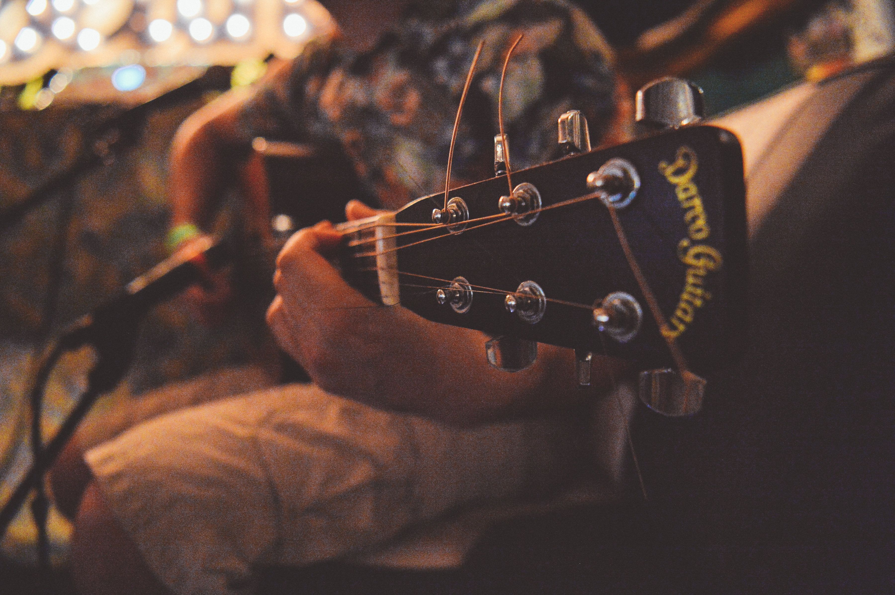 Primer plano del clavijero de una guitarra, con clavijas y el nombre de la marca.