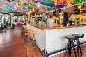 Eine Bar mit farbenfrohem Wandgemälde, Holzhockern und einer Speisekarte.