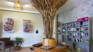 Une pièce décorée d’une sculpture en bois qui en constitue l’élément central, d’une bibliothèque et d’œuvres d’art accrochées aux murs.