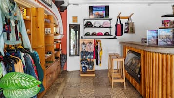 A boutique clothing store with wooden shelving, a variety of hats, and a small seating area.