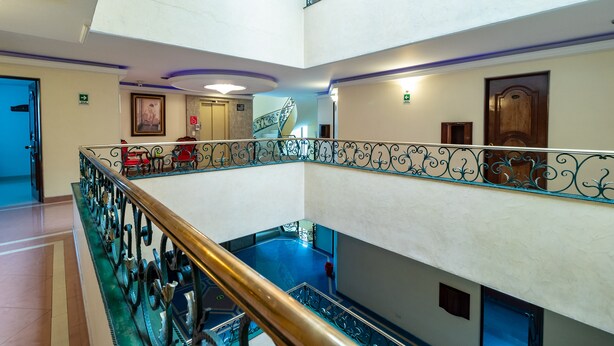 Ein mehrstöckiges Interieur mit einer zentralen Treppe, einem Poolbereich und einer Tür mit einem Schild.