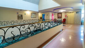 Eine Hotelhalle mit Treppe, einer Rezeption und einer Tür zum Aufzug.