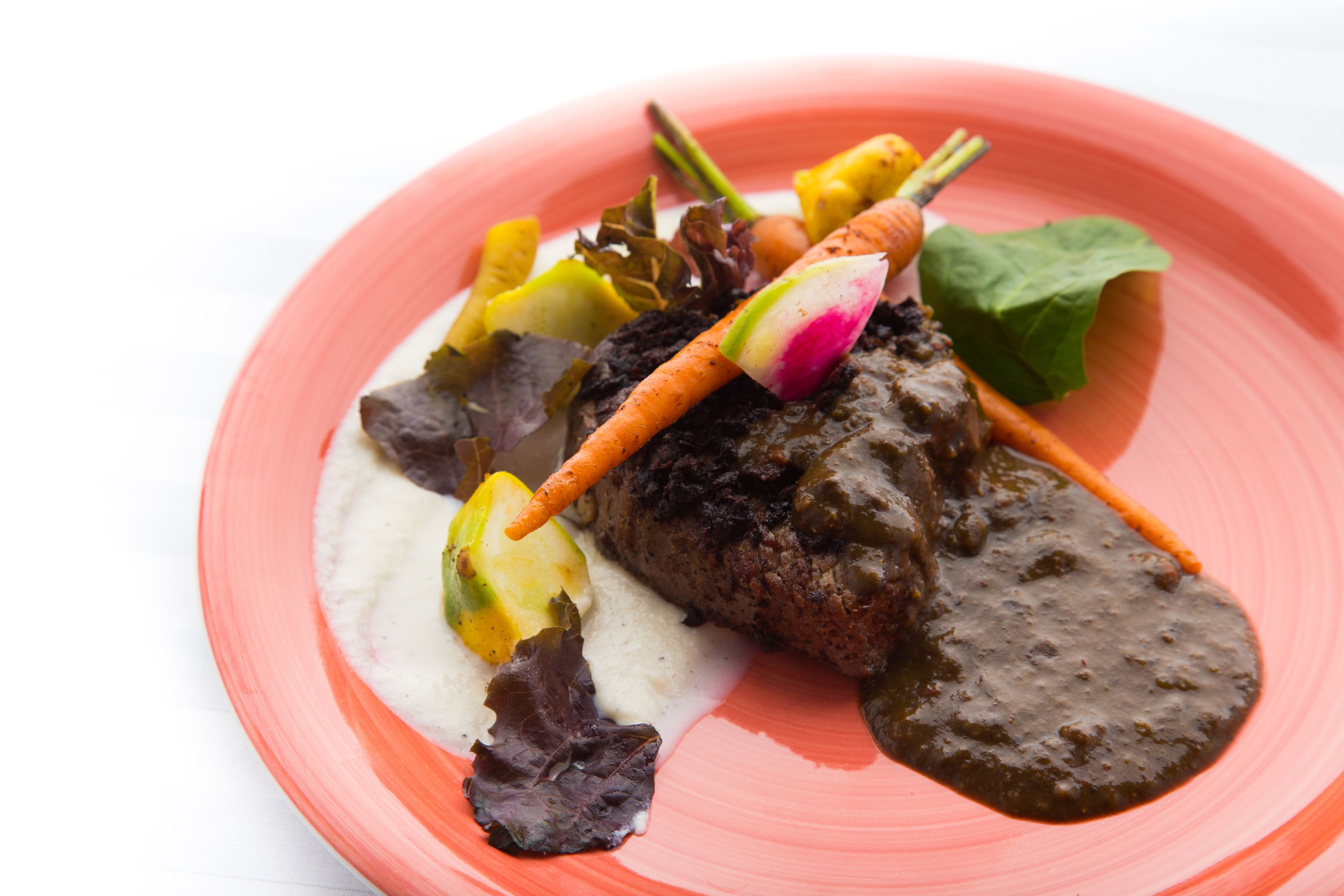 Un plato con carne, verduras y salsa.