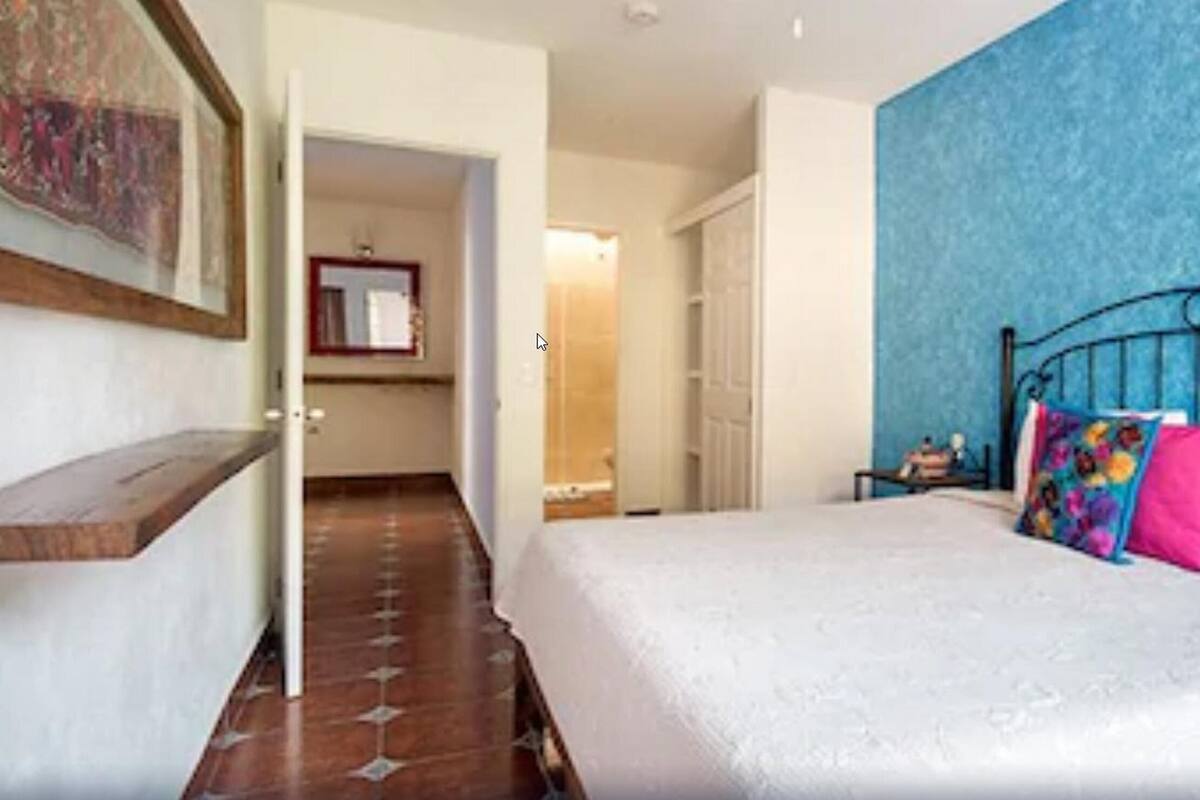 Une chambre à coucher avec un lit, une table de chevet et un mur bleu.