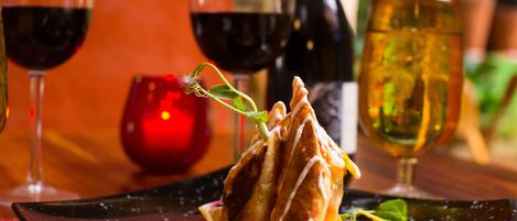 A dessert on a black plate with a sauce, surrounded by wine glasses and a candle.